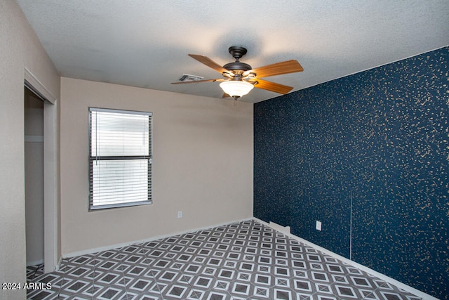 empty room featuring ceiling fan and a textured ceiling