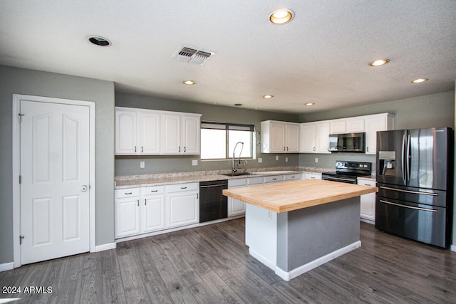 kitchen featuring wooden counters, a kitchen island, white cabinetry, black appliances, and dark hardwood / wood-style flooring