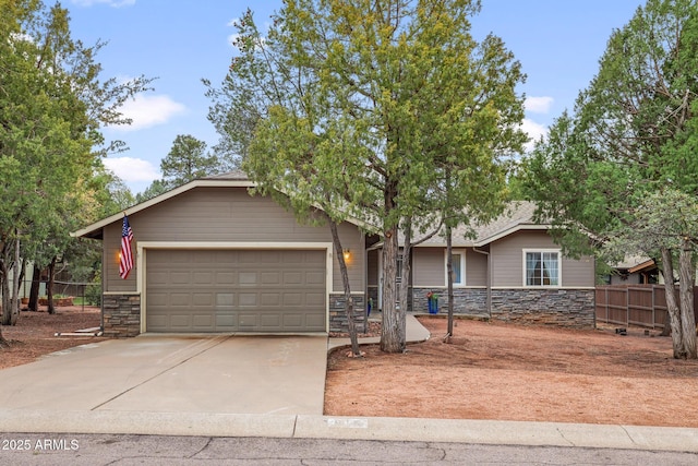 ranch-style home with an attached garage, fence, stone siding, and driveway