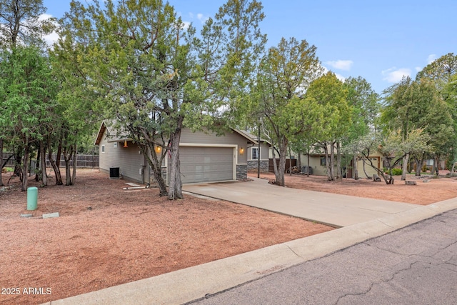 view of front of house featuring concrete driveway, cooling unit, fence, and a garage