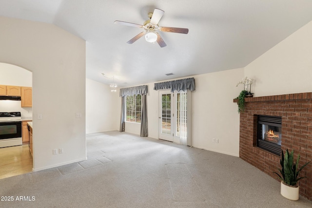 living area featuring visible vents, lofted ceiling, a fireplace, ceiling fan, and light carpet