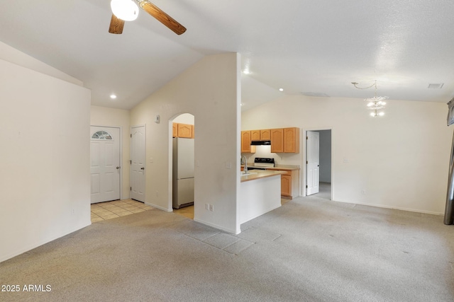 unfurnished living room featuring visible vents, arched walkways, vaulted ceiling, light carpet, and ceiling fan with notable chandelier