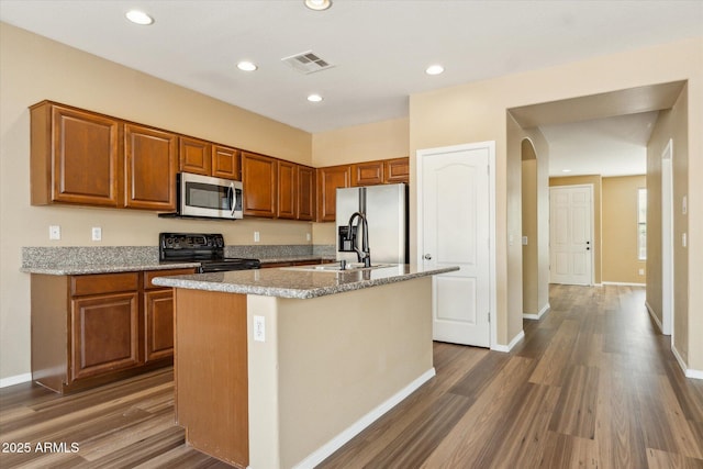 kitchen with stainless steel microwave, black range with electric cooktop, dark wood-style flooring, brown cabinetry, and recessed lighting