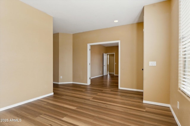 empty room with wood finished floors, baseboards, and recessed lighting