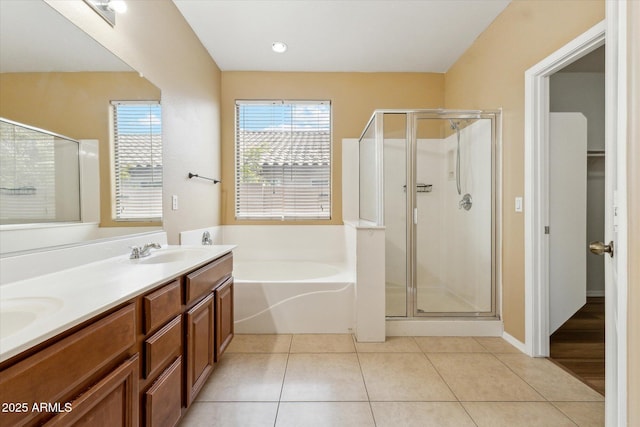 bathroom featuring a stall shower, a bath, double vanity, and tile patterned floors