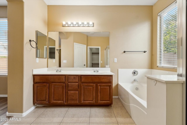 full bath featuring a garden tub, double vanity, tile patterned floors, and baseboards