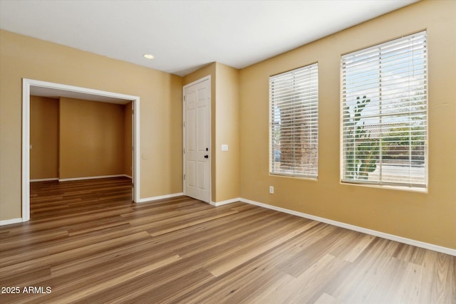 unfurnished room with light wood-style flooring, baseboards, and recessed lighting