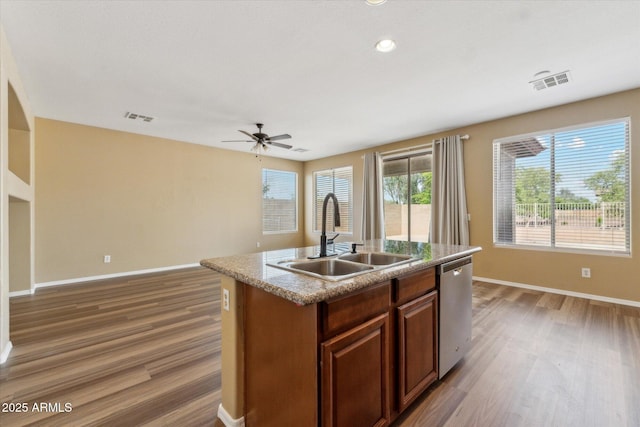 kitchen with a sink, stainless steel dishwasher, wood finished floors, baseboards, and recessed lighting