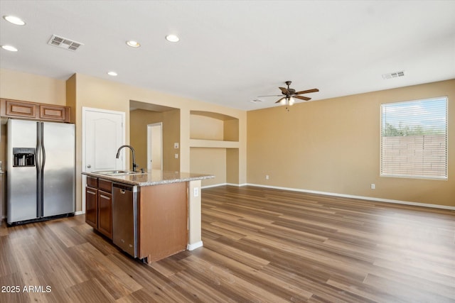 kitchen with appliances with stainless steel finishes, wood finished floors, a center island with sink, ceiling fan, and recessed lighting
