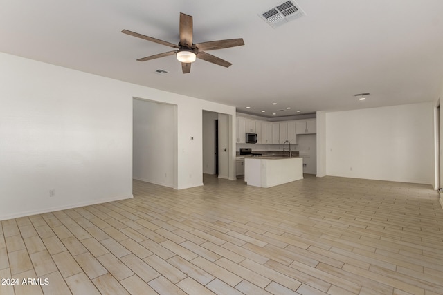 unfurnished living room with light hardwood / wood-style floors, sink, and ceiling fan