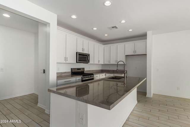 kitchen with sink, appliances with stainless steel finishes, light wood-type flooring, and white cabinets