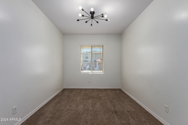 carpeted spare room with an inviting chandelier