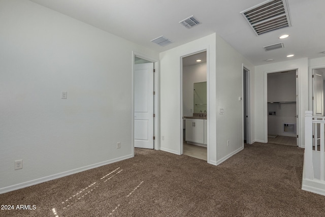 unfurnished bedroom featuring ensuite bathroom and carpet flooring