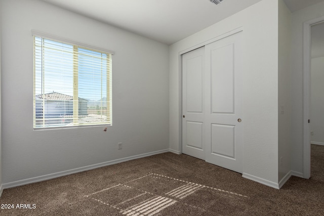 unfurnished bedroom with a closet and dark colored carpet