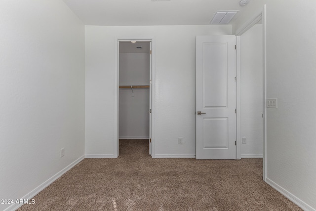 unfurnished bedroom with carpet, a walk in closet, and a closet