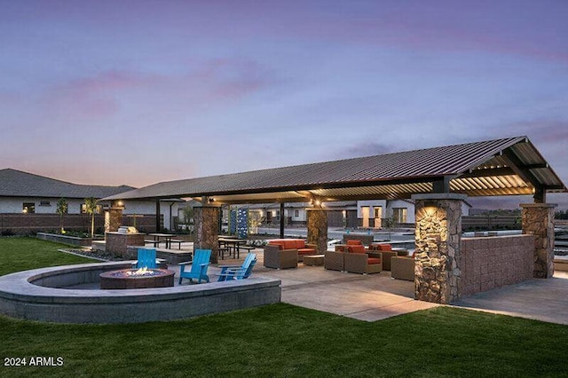 patio terrace at dusk featuring an outdoor fire pit and a yard