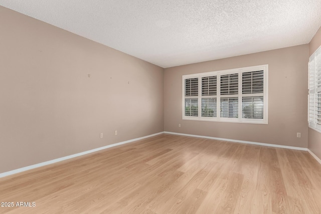 unfurnished room with light wood-style flooring, baseboards, and a textured ceiling