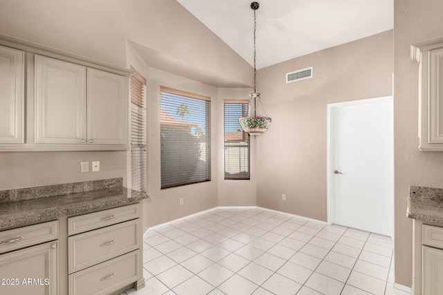 kitchen featuring vaulted ceiling, decorative light fixtures, light tile patterned floors, and visible vents