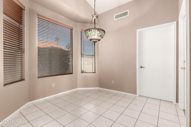 unfurnished room featuring light tile patterned floors, visible vents, baseboards, and vaulted ceiling