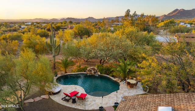 pool at dusk with a mountain view and a patio area