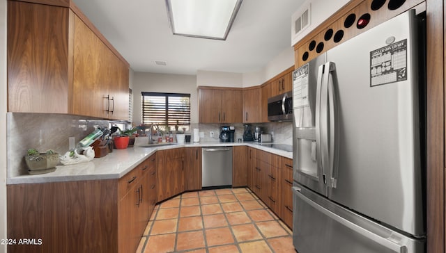 kitchen with backsplash, sink, light tile patterned floors, and stainless steel appliances