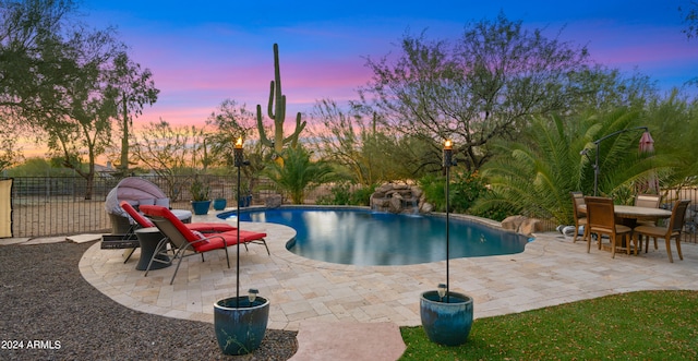 pool at dusk featuring a patio