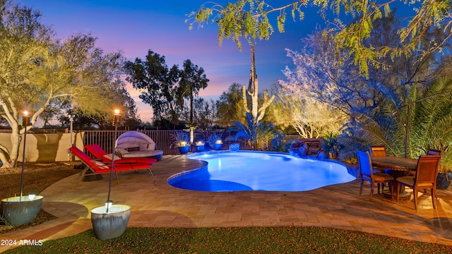 pool at dusk with a patio area