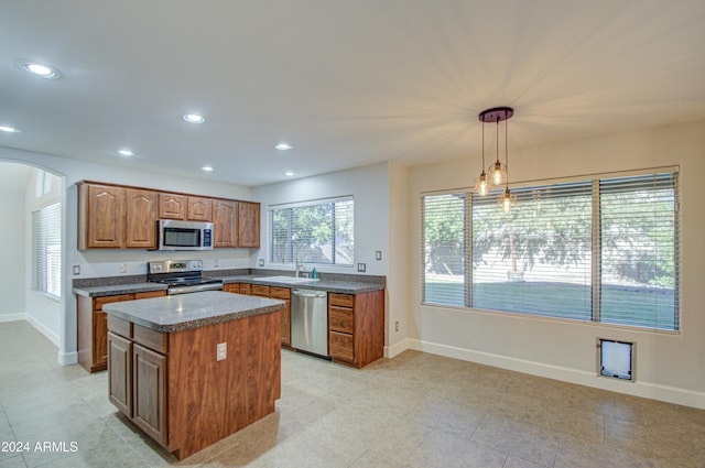 kitchen featuring light tile patterned floors, stainless steel appliances, a center island, decorative light fixtures, and sink