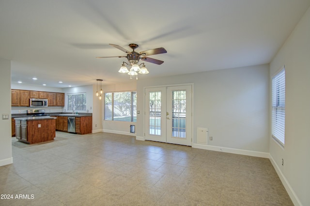 kitchen featuring ceiling fan, a kitchen island, hanging light fixtures, appliances with stainless steel finishes, and french doors