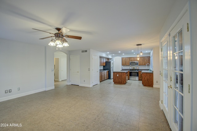 kitchen featuring ceiling fan, a center island, sink, hanging light fixtures, and stainless steel appliances