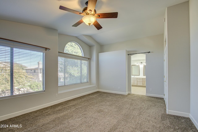 spare room featuring ceiling fan, light colored carpet, and vaulted ceiling