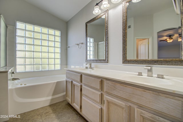 bathroom with vaulted ceiling, tile patterned flooring, a washtub, and vanity