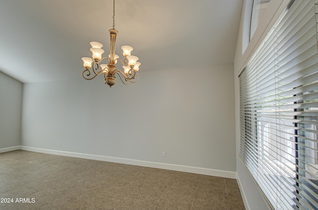 tiled spare room with a notable chandelier