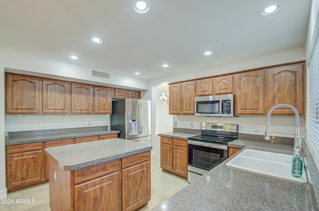 kitchen with light tile patterned floors, appliances with stainless steel finishes, sink, and a kitchen island