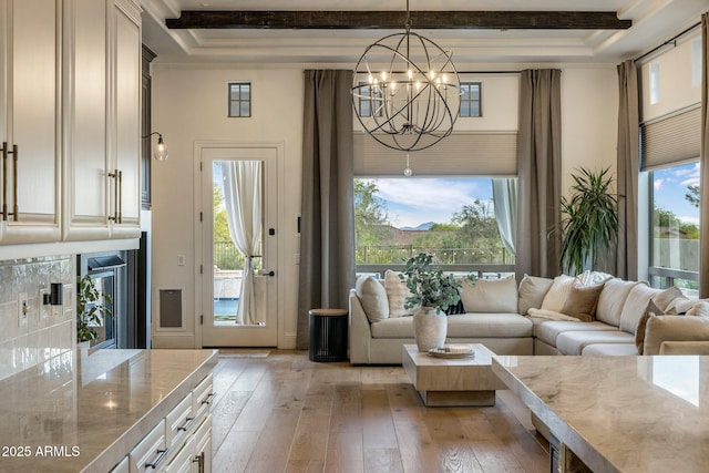 living area featuring light wood-style flooring, a notable chandelier, and a wealth of natural light