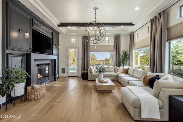 living room with light wood-style floors, a glass covered fireplace, beam ceiling, and a notable chandelier