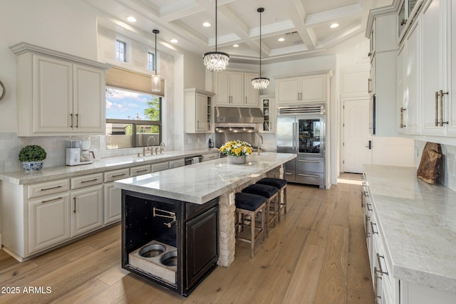 kitchen with a towering ceiling, a breakfast bar area, a sink, coffered ceiling, and appliances with stainless steel finishes