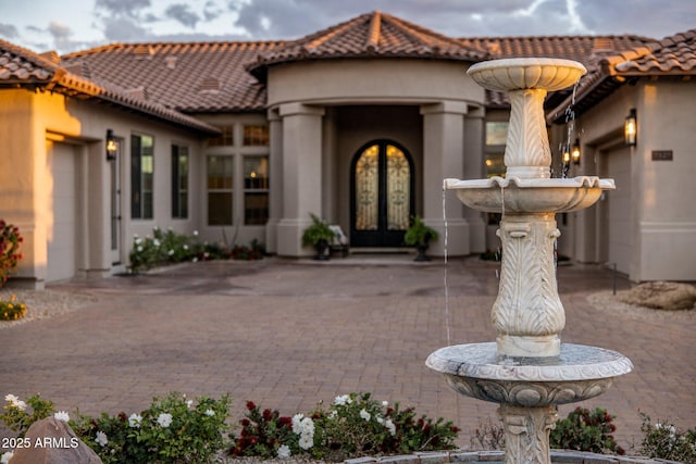 doorway to property featuring french doors, a tile roof, and stucco siding