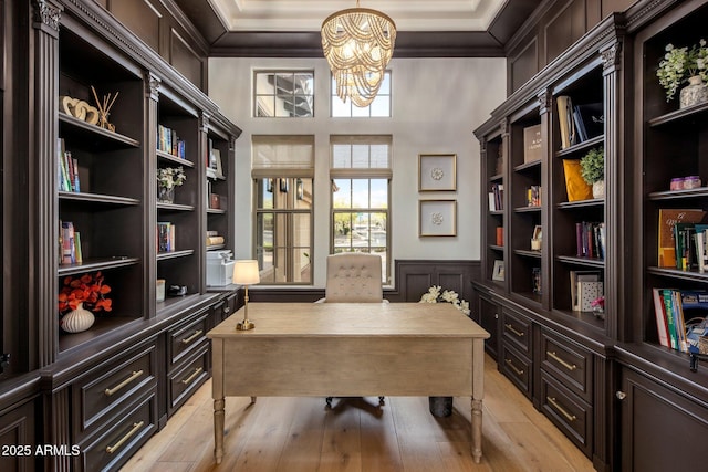 office featuring an inviting chandelier, a wainscoted wall, light wood finished floors, and a decorative wall