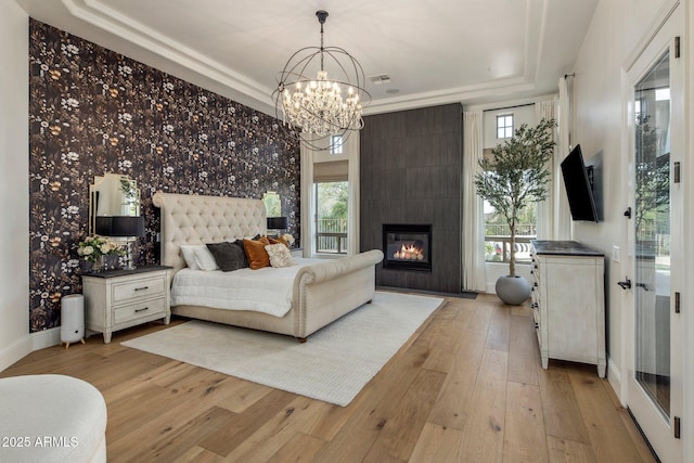 bedroom with a raised ceiling, multiple windows, light wood-type flooring, and a chandelier