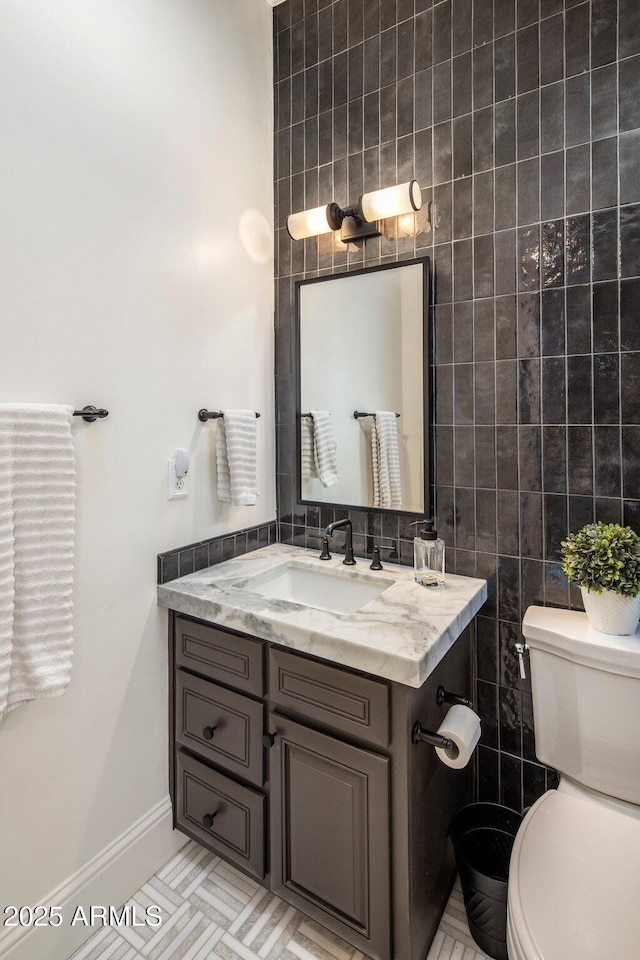 bathroom with vanity, baseboards, toilet, and tile walls