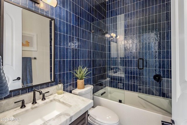 full bath with vanity, decorative backsplash, toilet, tile walls, and bath / shower combo with glass door
