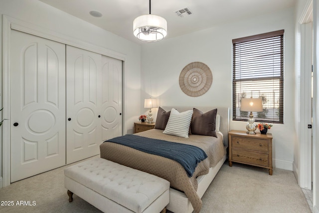 bedroom featuring light colored carpet, visible vents, and a closet