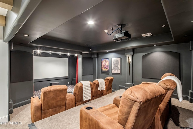 cinema room with visible vents, a raised ceiling, and carpet
