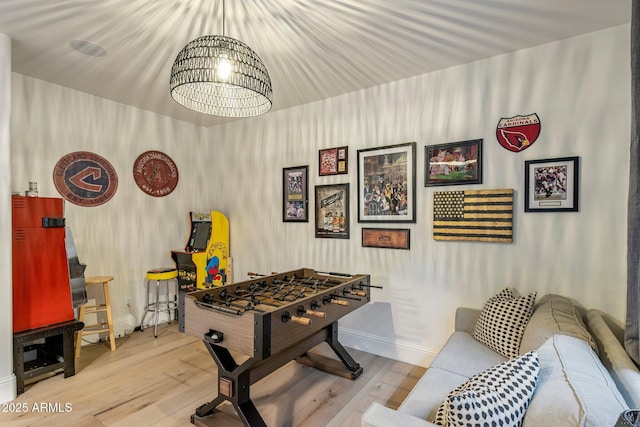 rec room featuring baseboards, wood finished floors, and a notable chandelier