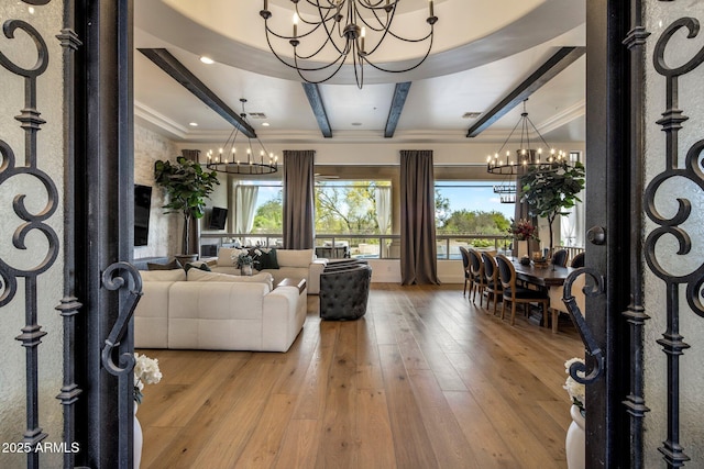 living area featuring crown molding, beamed ceiling, a chandelier, and hardwood / wood-style flooring