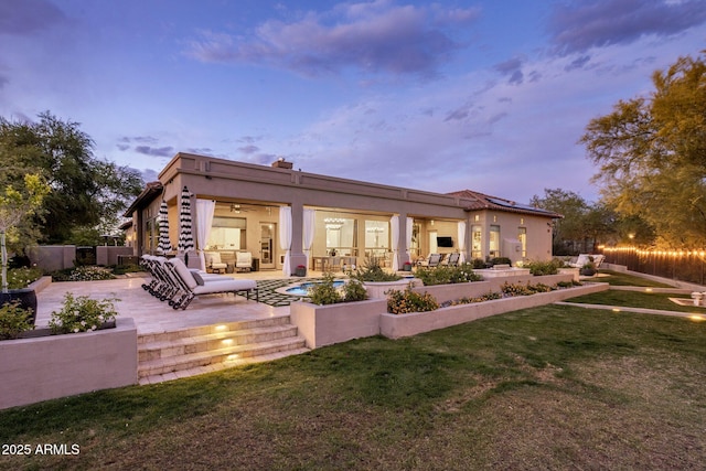 rear view of house with an outdoor hangout area, a patio, stucco siding, and a lawn