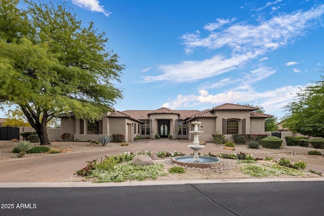 mediterranean / spanish home with curved driveway, stucco siding, and a tiled roof