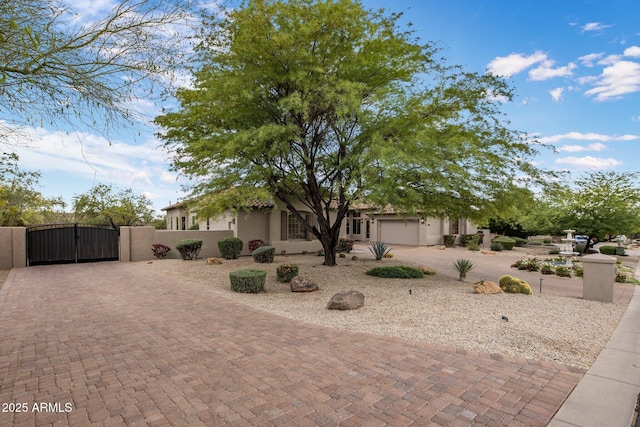 view of front of property featuring a gate, a garage, decorative driveway, fence, and stucco siding