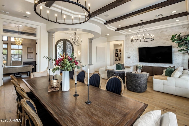 dining area featuring wood-type flooring, arched walkways, a chandelier, decorative columns, and beamed ceiling